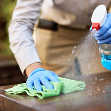 Cleaning a wooden surface with a spray bottle and cloth.
